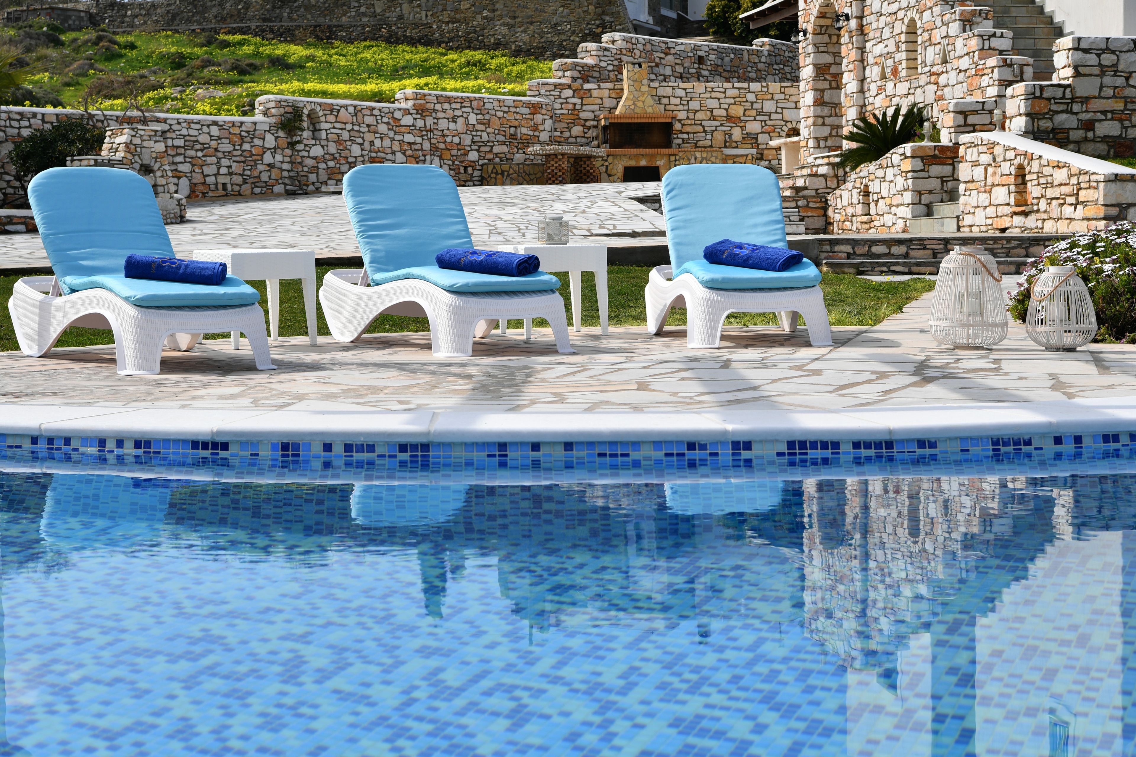 A poolside area with lounge chairs and a stone wall in the background.