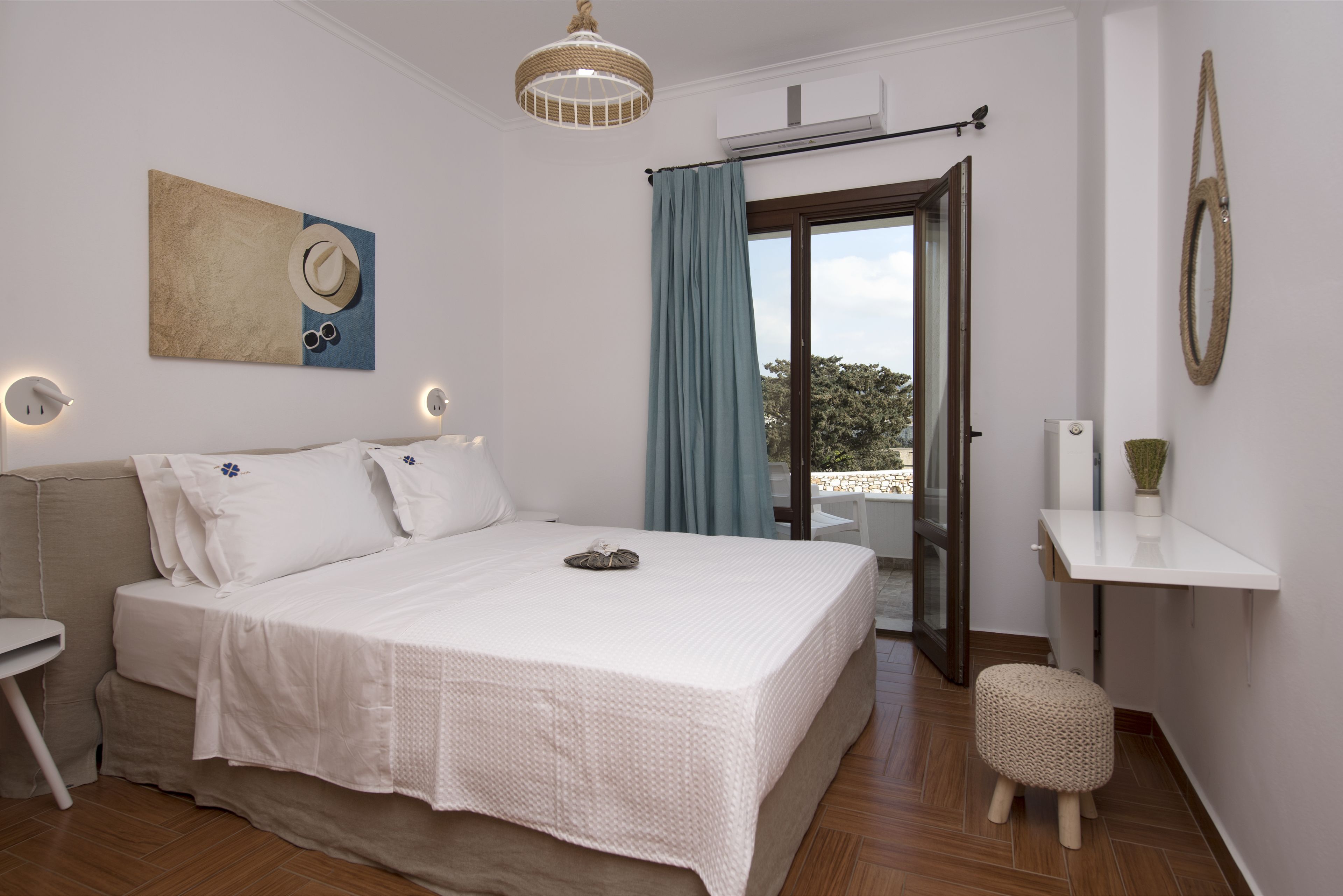 A bedroom with a bed, bedside table, and a view of the outdoors.