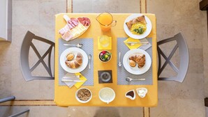 A breakfast table with plates of food, a jug of orange juice, and various breakfast items. - Domus Japigia (Ugento)