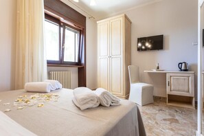 A hotel room with a bed, a TV, a desk with a kettle, and a cabinet. - Domus Japigia (Ugento)