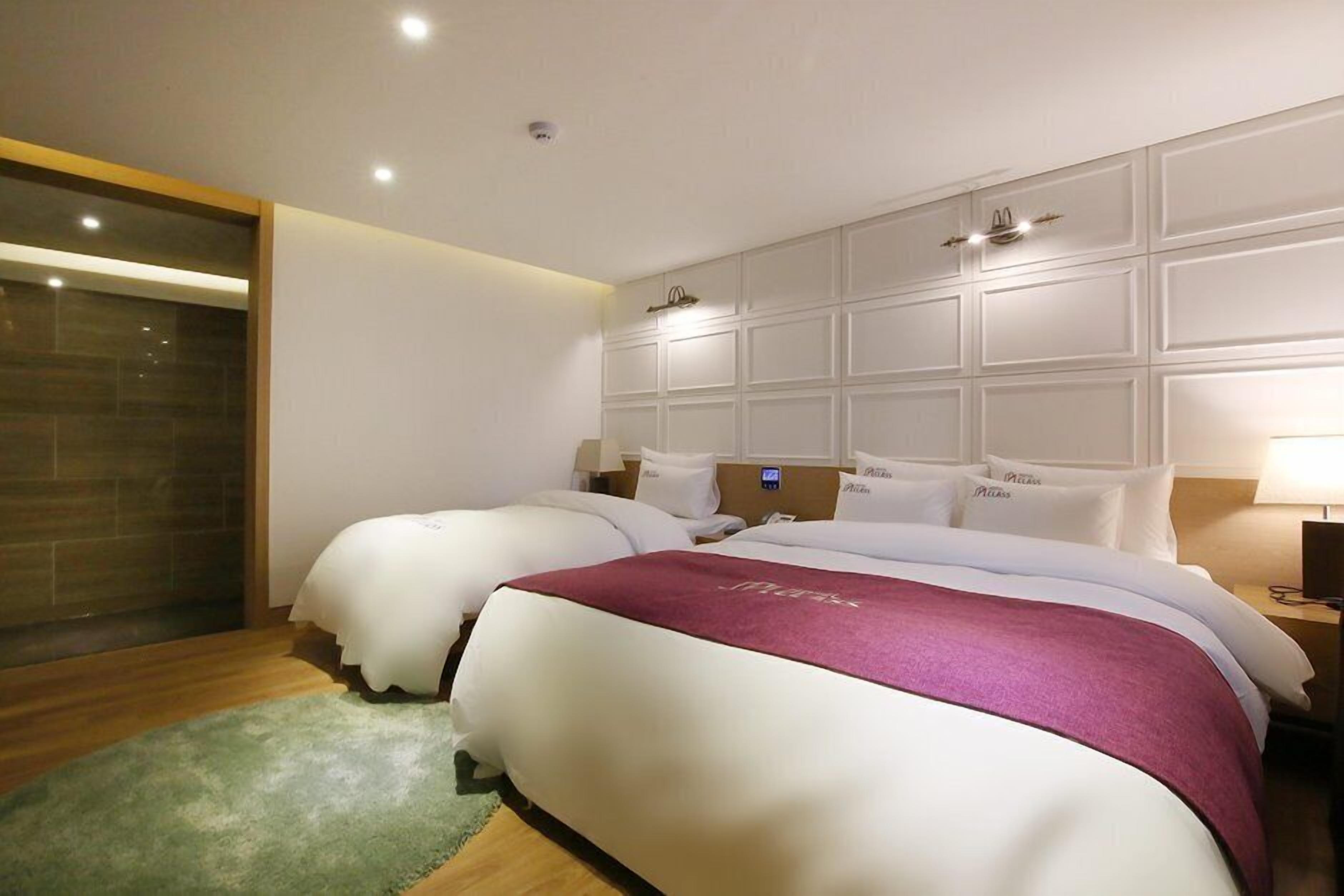 Habitación de hotel con dos camas, un espejo grande y suelo de madera.