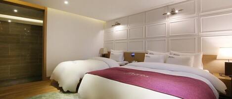 Habitación de hotel con dos camas, un espejo grande y suelo de madera.