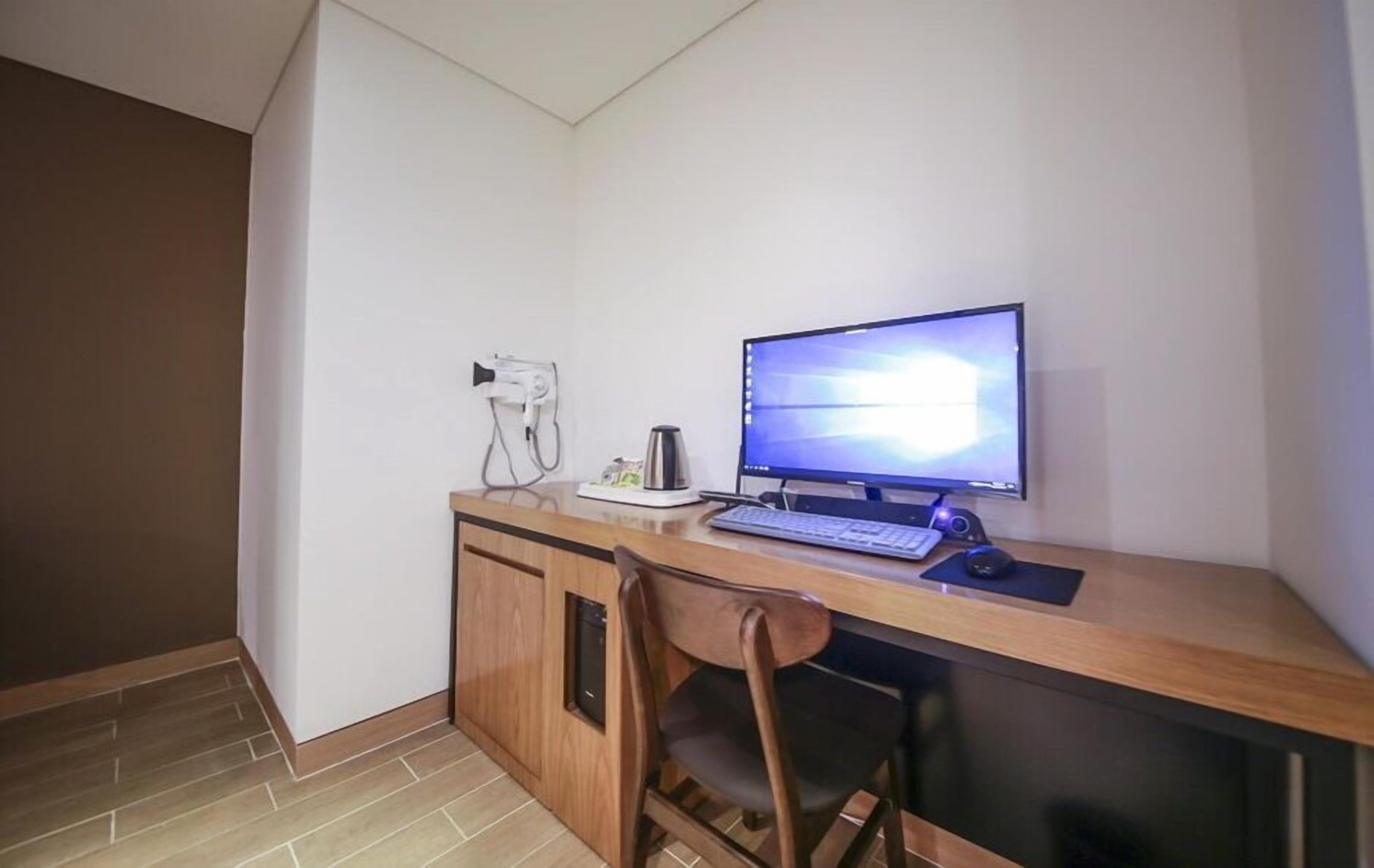 A small, modern office space with a wooden desk, a computer, and a chair.
