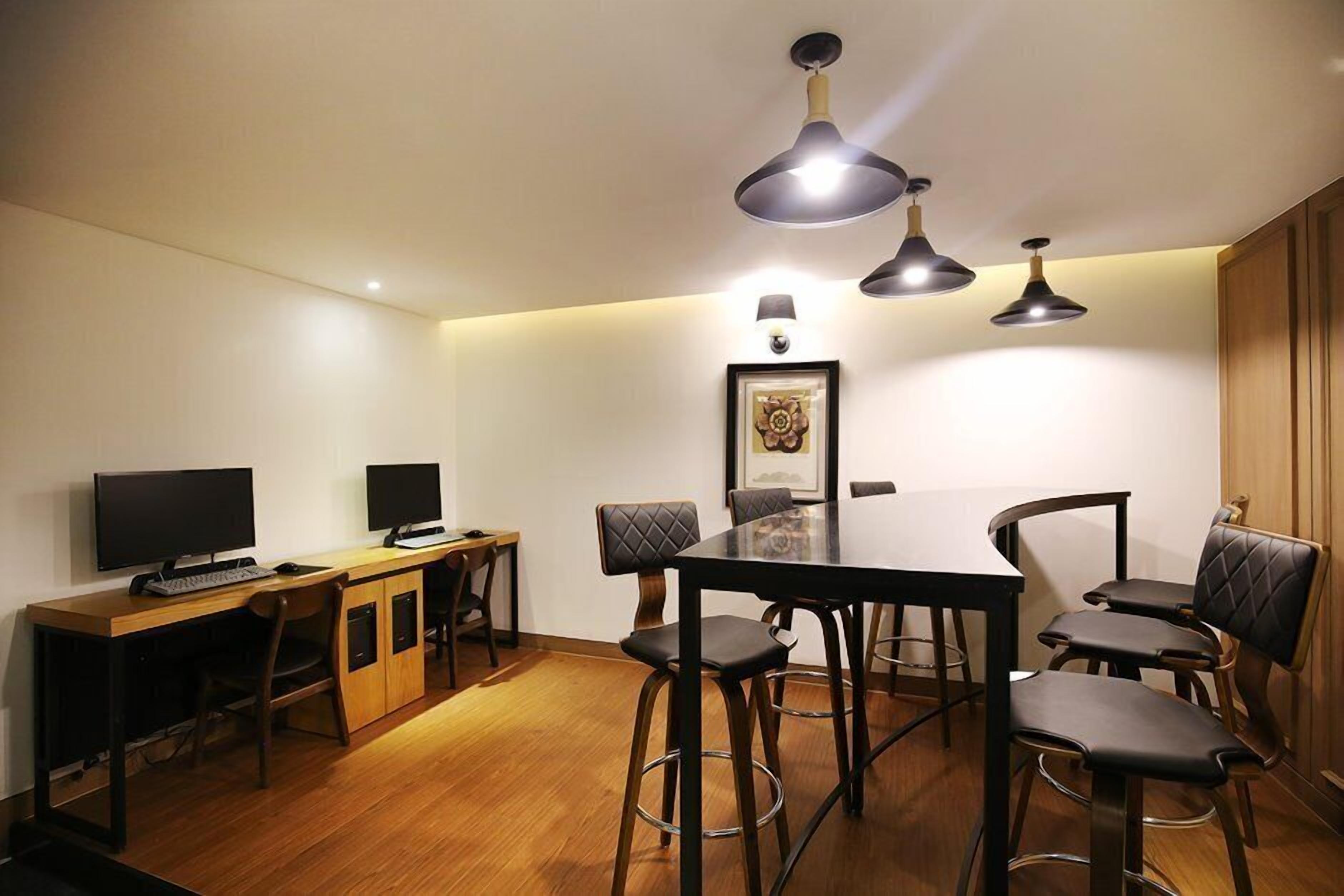 A modern dining area with a wooden table, black chairs, and pendant lighting.