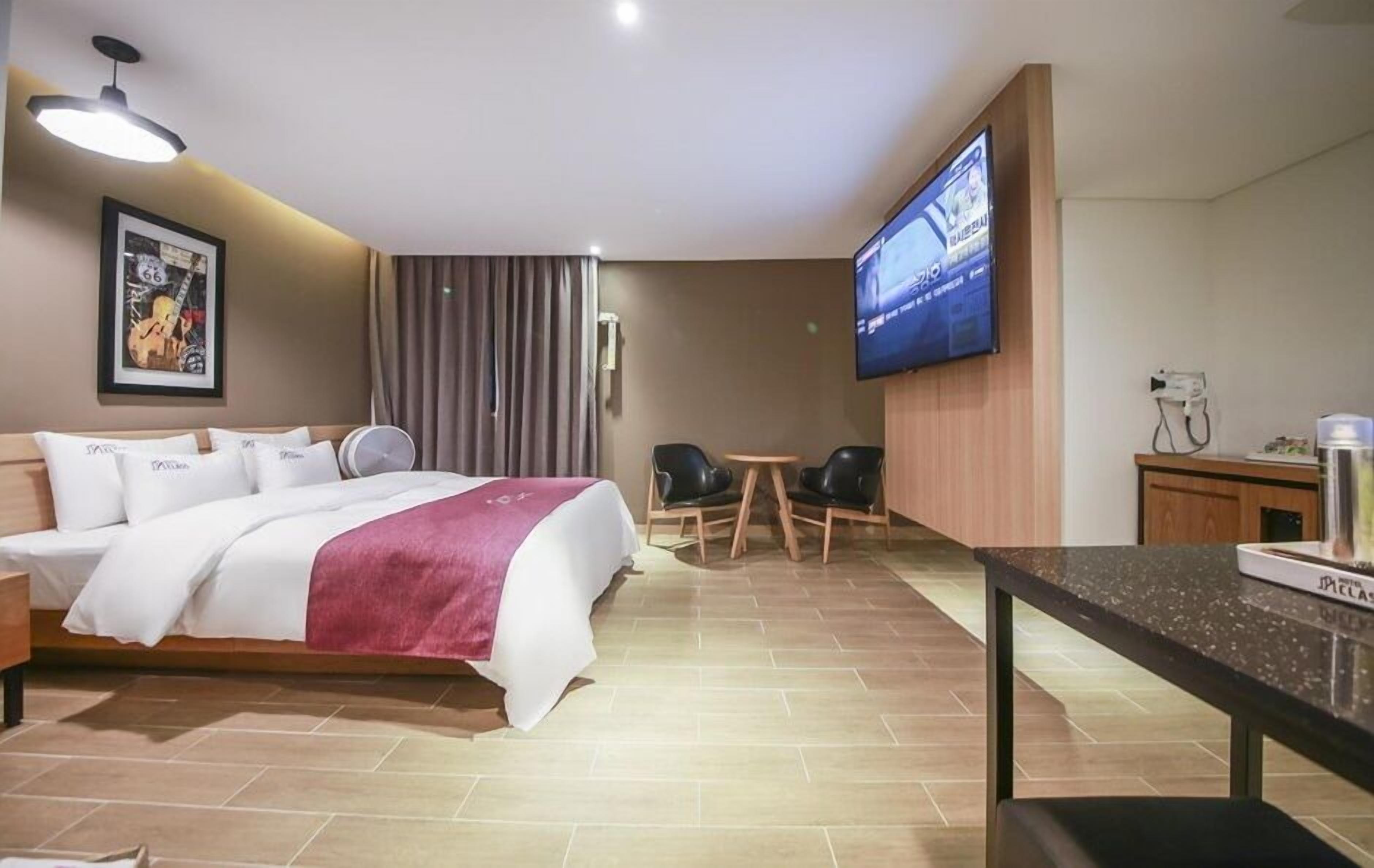 A hotel room with a bed, a desk, a TV, and a chair.