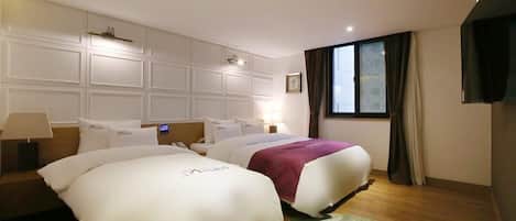 A hotel room with two beds, a large window, and a flat-screen TV.
