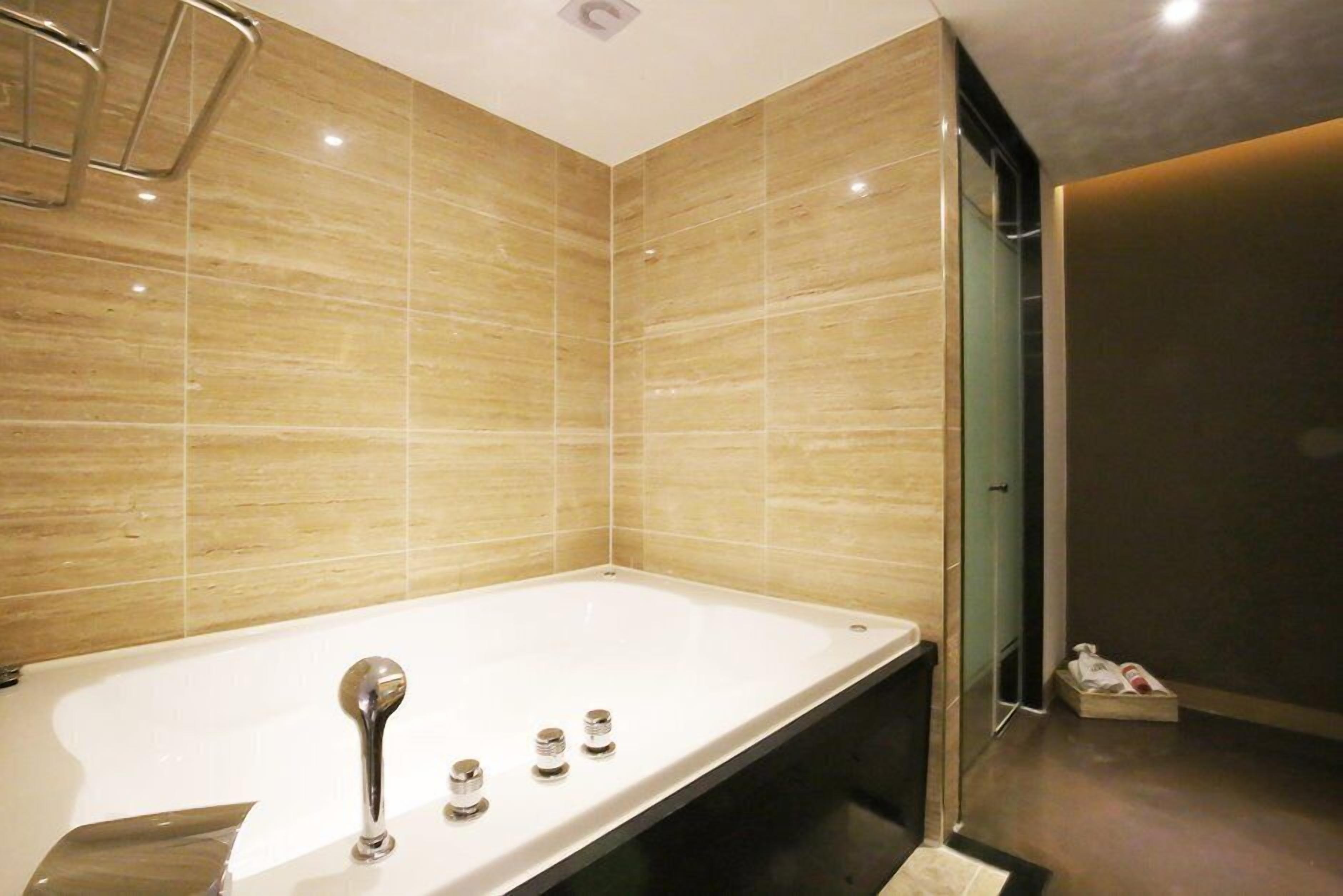 Ein modernes Badezimmer mit einer großen Badewanne, einer Duschkabine und einer Glastür zu einem begehbaren Kleiderschrank.