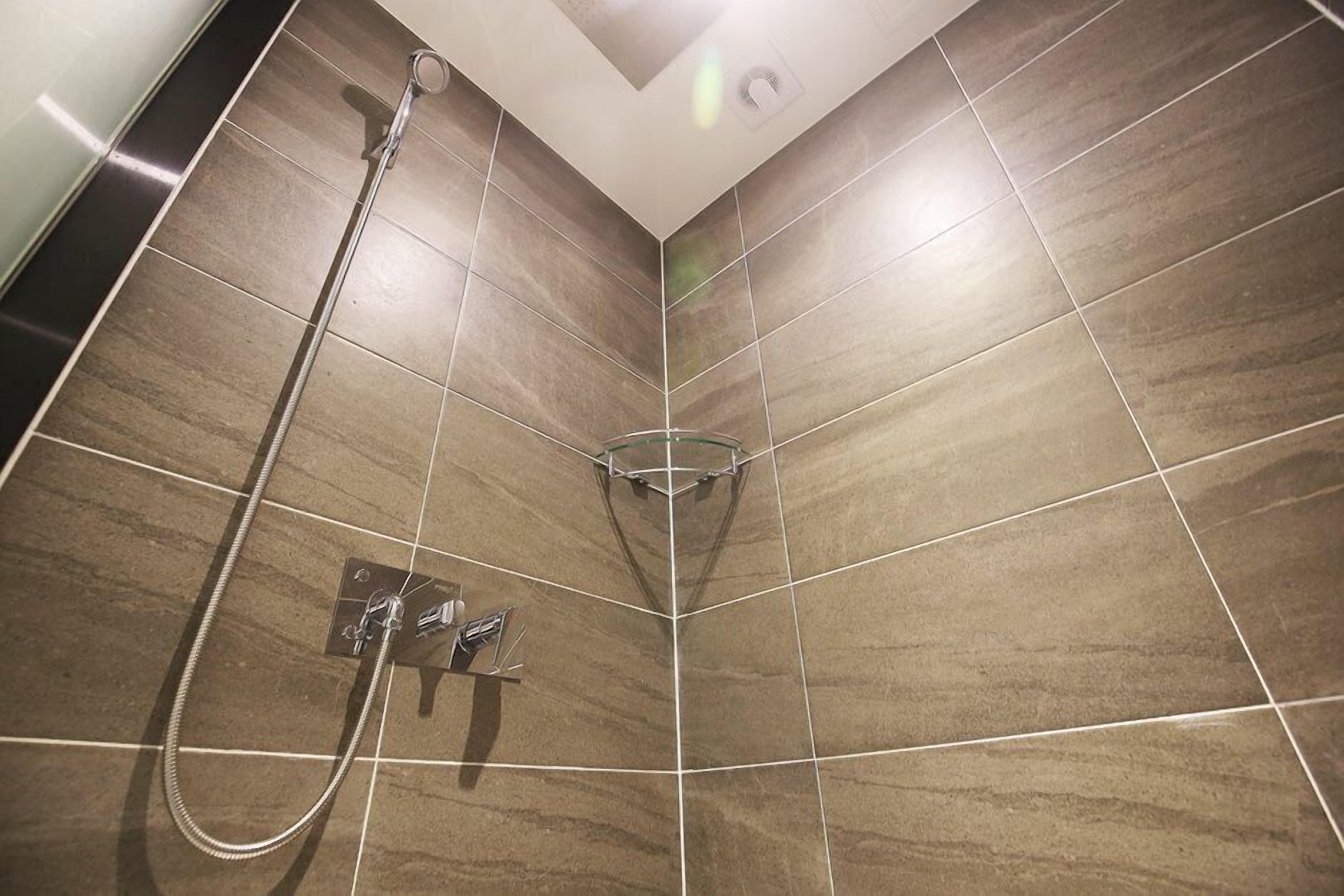 Zona de ducha con cabezal de ducha con recinto de vidrio y ducha de mano.