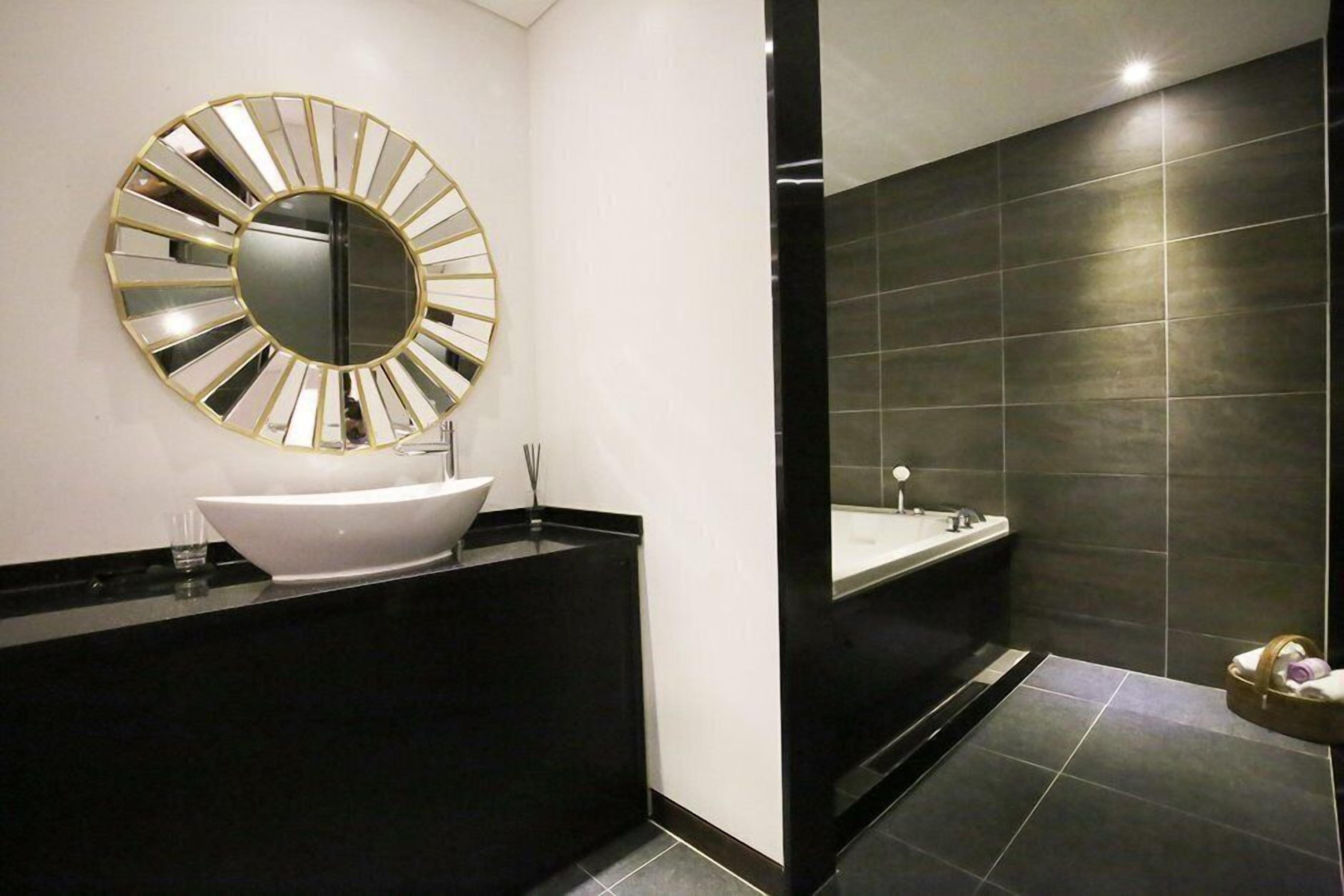 Un baño moderno con un lavamanos blanco, un espejo grande y una bañera.