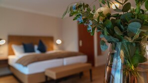 Quarto moderno com uma cama grande, mesas de cabeceira e um vaso com flores.