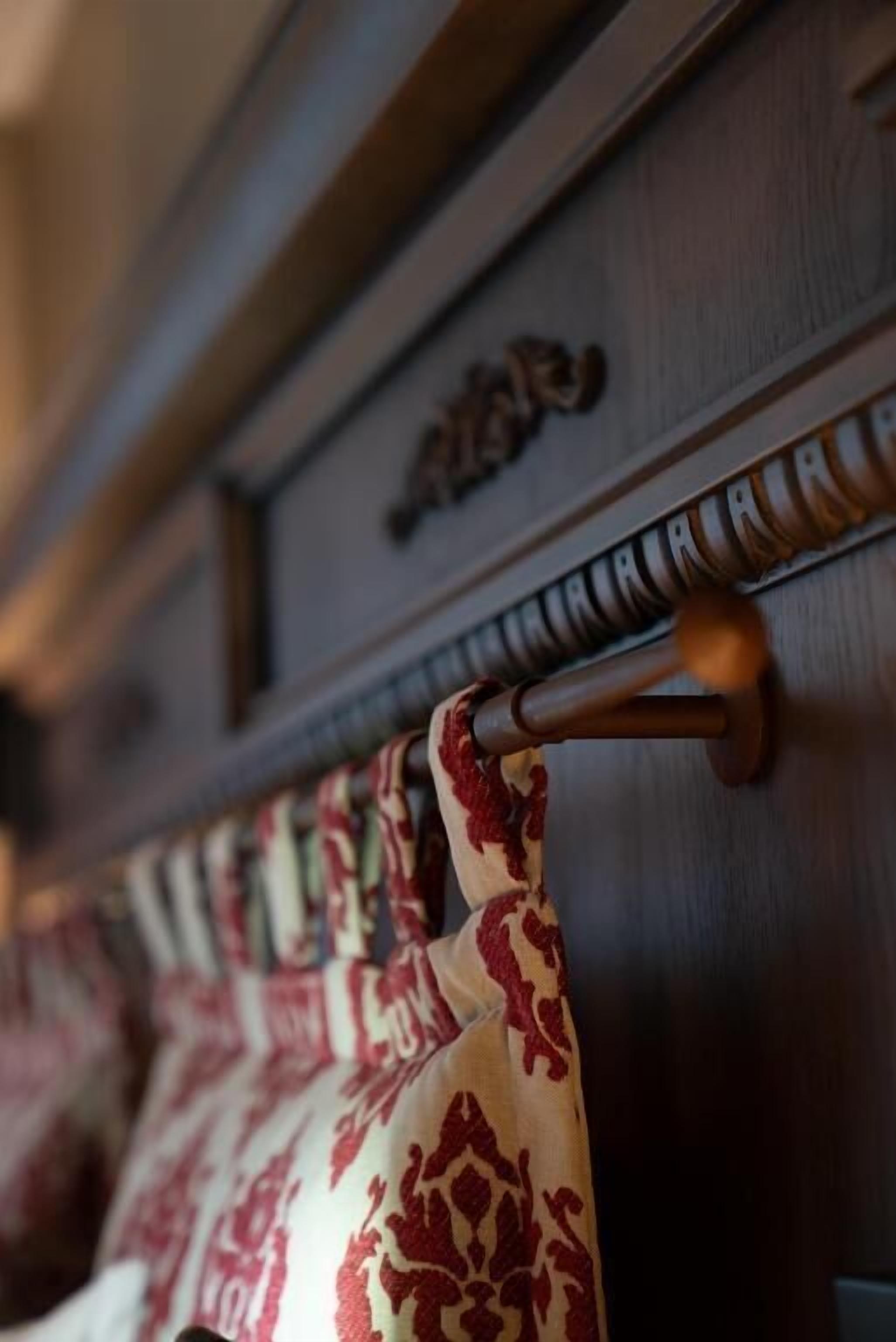 A wooden panel with a decorative metal handle and a patterned curtain.
