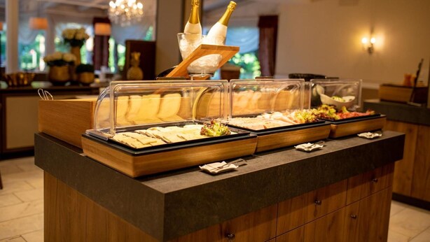 Buffet com diversos alimentos e uma garrafa de champanhe.