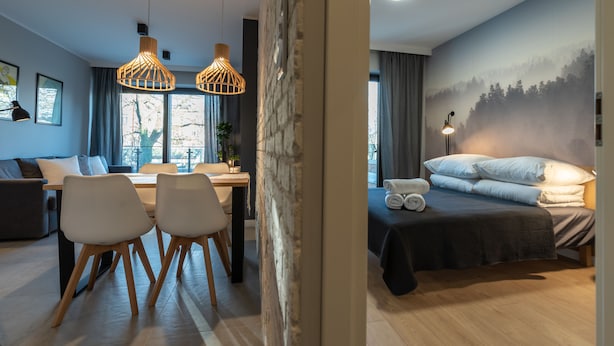 A modern hotel room with a bed, a desk, two chairs, and a dining area. - City Lights Apartments - Rakowicka 15 (Kraków)