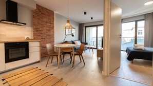 A modern apartment with a kitchen, dining area, and a balcony with a bed. - City Lights Apartments - Rakowicka 15 (Kraków)