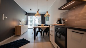A modern kitchen with a dining area, featuring pendant lights, a stove, and a coffee maker. - City Lights Apartments - Rakowicka 15 (Kraków)