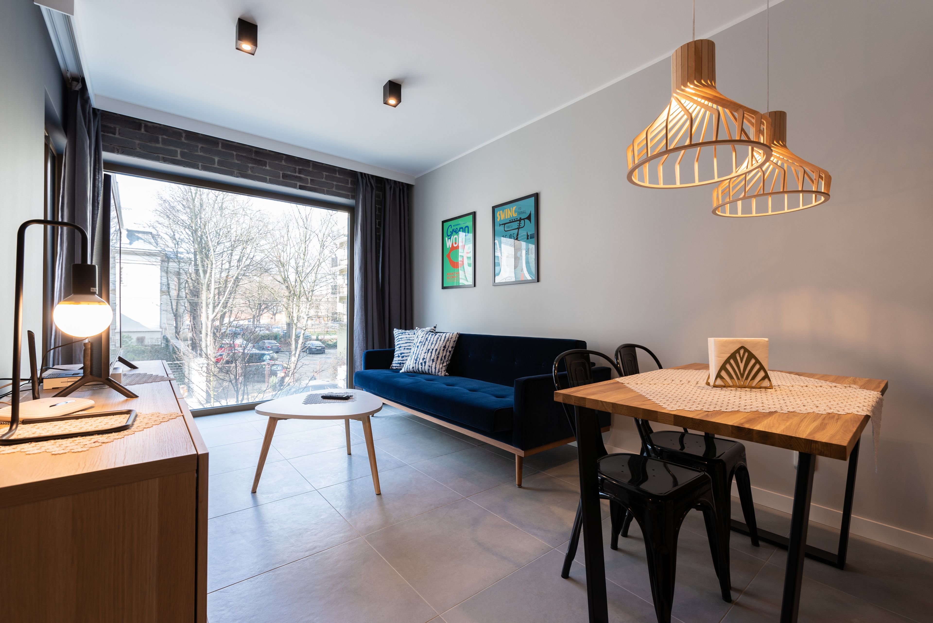 Sala de estar moderna com sofá, mesa de jantar e luminárias pendentes.