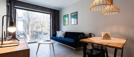 Un salon moderne avec un canapé, une table à manger et des luminaires suspendus.