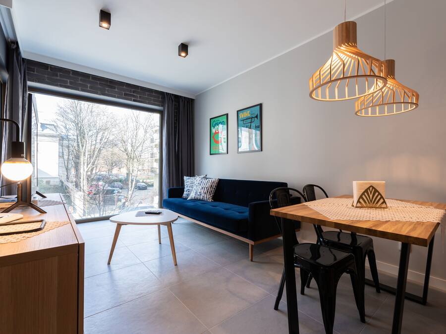 Sala de estar moderna com sofá, mesa de jantar e luminárias pendentes.