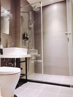 A modern bathroom with a glass-enclosed shower, a white sink, and a toilet.