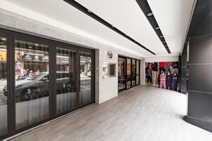 Un interior moderno con un diseño limpio y minimalista, que presenta un corredor espacioso, escaparates de vidrio y una exhibición de percheros de ropa.