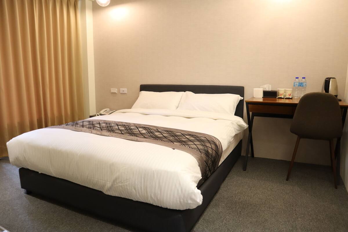 A hotel room with a bed, a desk, and a chair.