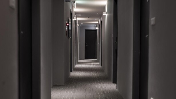 A long, narrow hallway with a patterned floor and doors on both sides. - Tag inn (Taoyuan City)
