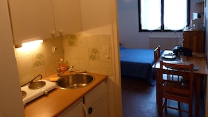 A compact kitchen with a sink, a stove, and a dining area with a chair and table. - Studio 2 people with parking Annecy (Annecy)