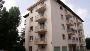 A multi-story residential building with balconies, a parking area, and a few parked motorcycles. - Studio 2 people with parking Annecy (Annecy)