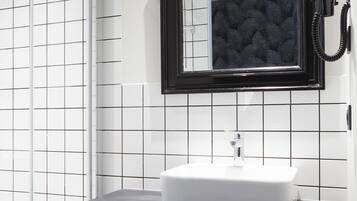 Un baño con un lavamanos blanco, encimera negra y un espejo enmarcado.
