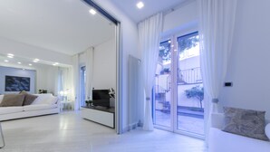 A modern living room with a sofa, TV, and a sliding glass door leading to an outdoor area. - JOIVY Nervi Charming Flat Santarosa (Genoa)