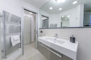 A modern bathroom with a double sink, a large mirror, and a towel rack.