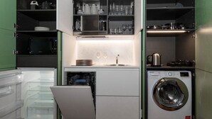 Une cuisine compacte équipée d’un lave-vaisselle, d’une machine à laver et d’un four à micro-ondes.