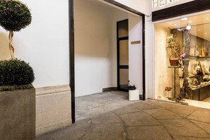 A storefront with a minimalist design, featuring a display of shoes and handbags. - JOIVY 9 Montenapo (Milan)
