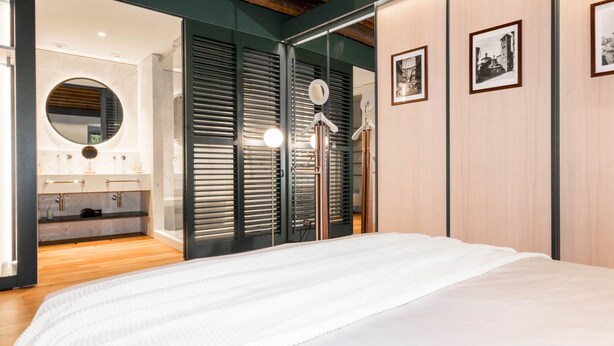 Une chambre moderne avec un grand lit, un miroir et une armoire à portes coulissantes.