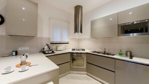 A modern kitchen with stainless steel appliances, a built-in oven, and a compact layout. - JOIVY Golf Garlenda - Charming Villa Guest House (Garlenda)