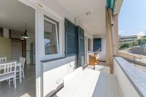 A balcony with a dining table and chairs, a sofa, and a view of the street and buildings. - JOIVY Sestri Levante Holiday Flat (Sestri Levante)
