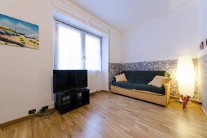 A living room with a flat-screen TV, a sofa, a lamp, and a painting on the wall. - JOIVY Couzy Flat Albaro a Pochi Minuti dal Mare (Genoa)