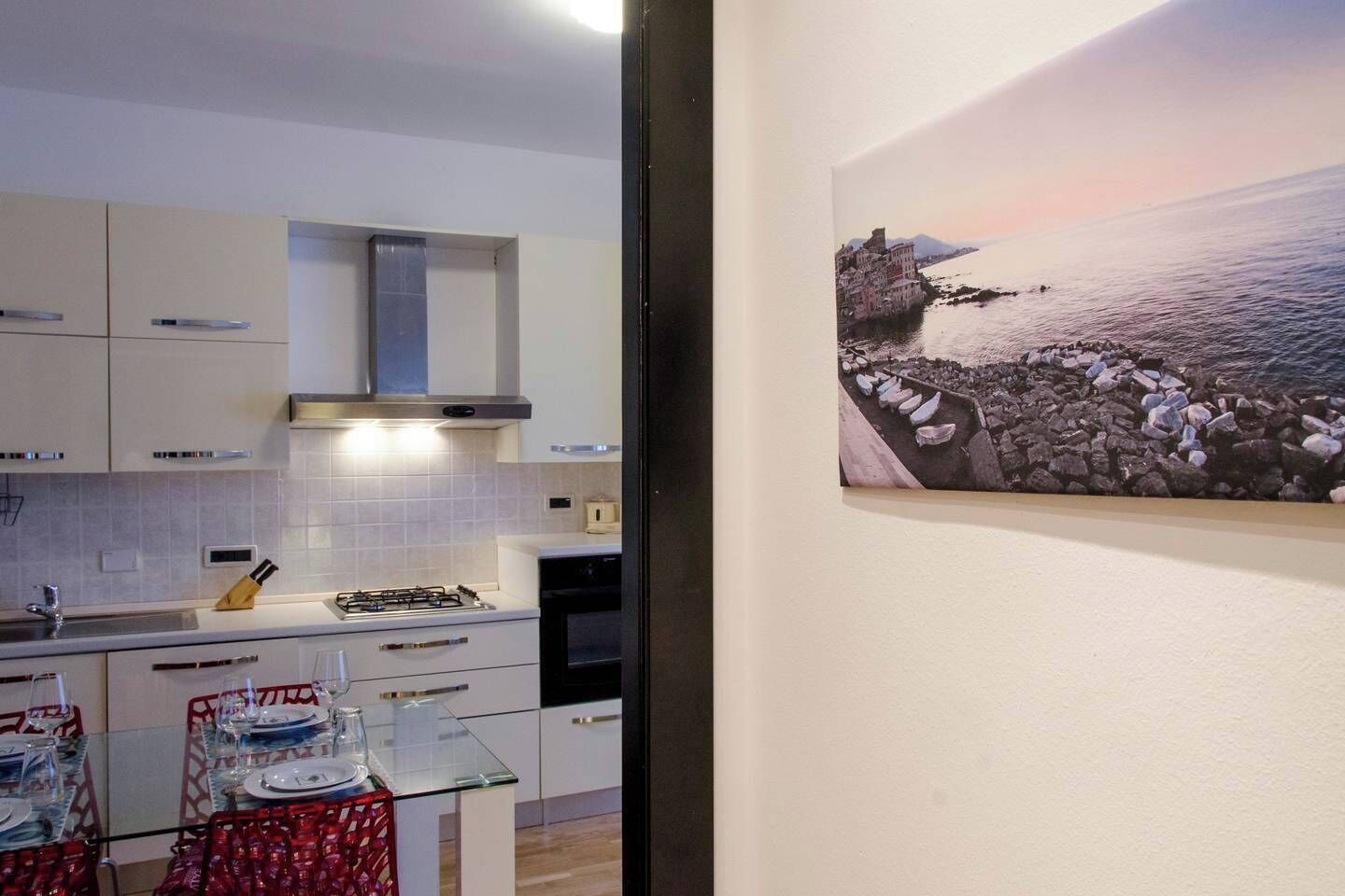 A modern kitchen with white cabinets, a gas stove, and a dining area with a glass table and chairs.