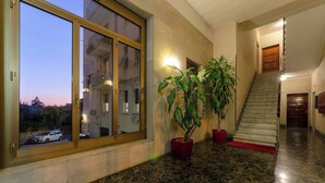 A spacious hallway with a large window, potted plants, a staircase, and a polished stone floor. - JOIVY Family Flat Vicino al Mare a Genova Quinto (Genoa)