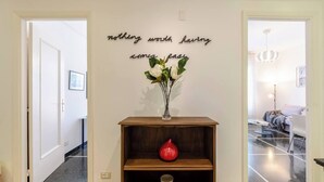 A hallway with a wooden console table, a vase with flowers, and a motivational quote on the wall. - JOIVY Family Flat Vicino al Mare a Genova Quinto (Genoa)