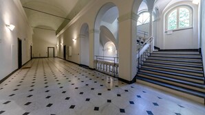 Un vaste hall d’entrée doté d’un sol à motifs, de plafonds en arc de cercle et d’un escalier muni d’une rampe.
