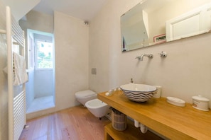 A bathroom with a wooden vanity, a vessel sink, a toilet, and a shower. - JOIVY il Cielo di Laura (Genoa)