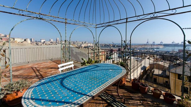 Une terrasse sur le toit avec une piscine à carrelage bleu, une rambarde en métal et des plantes en pot.