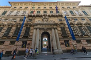 A historic building with classical architecture, featuring a central archway and columns, and banners indicating it is a museum. - JOIVY il Cielo di Laura (Genoa)