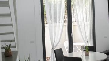 A modern dining area with a round table, black chairs, and potted plants.