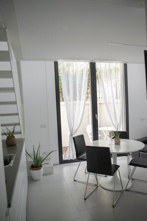 Een moderne eethoek met een ronde tafel, zwarte stoelen en potplanten.
