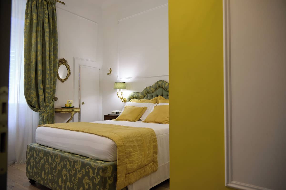 A bedroom with a bed, a bedside table, a lamp, and a mirror.