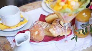 A table with pastries, a fruit salad, a glass of juice, and a cup of coffee.