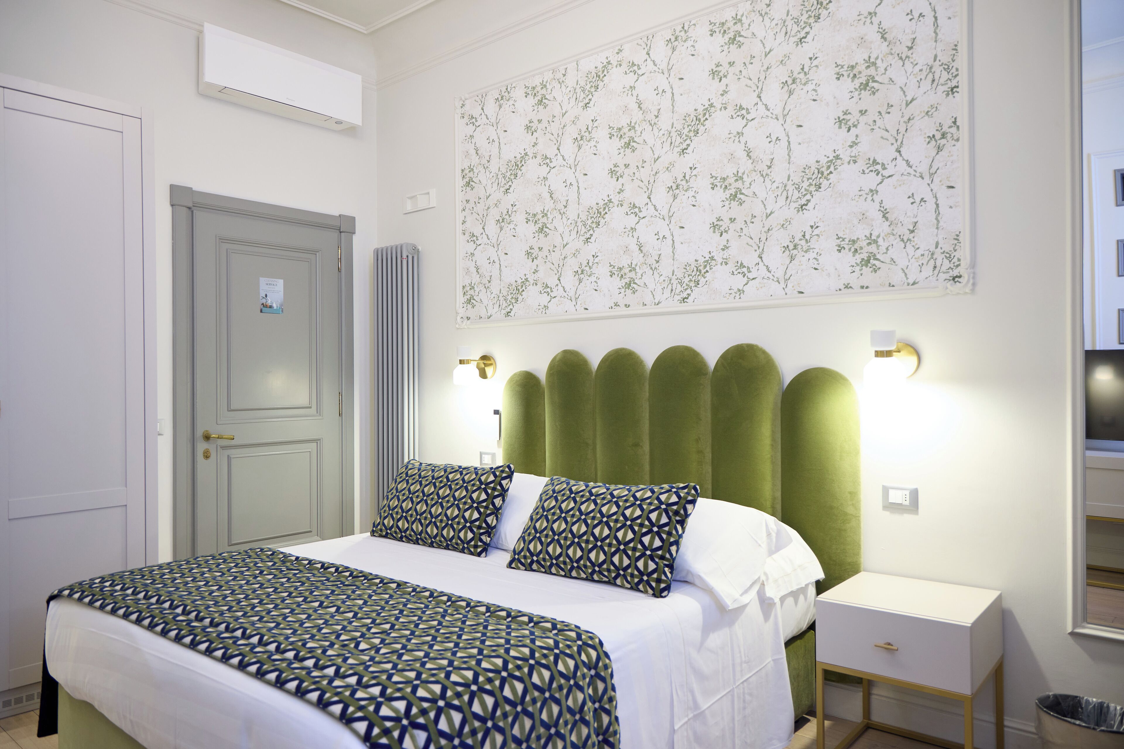 Ein Schlafzimmer mit Bett, Nachttisch, Wandlampe und einer Tür.