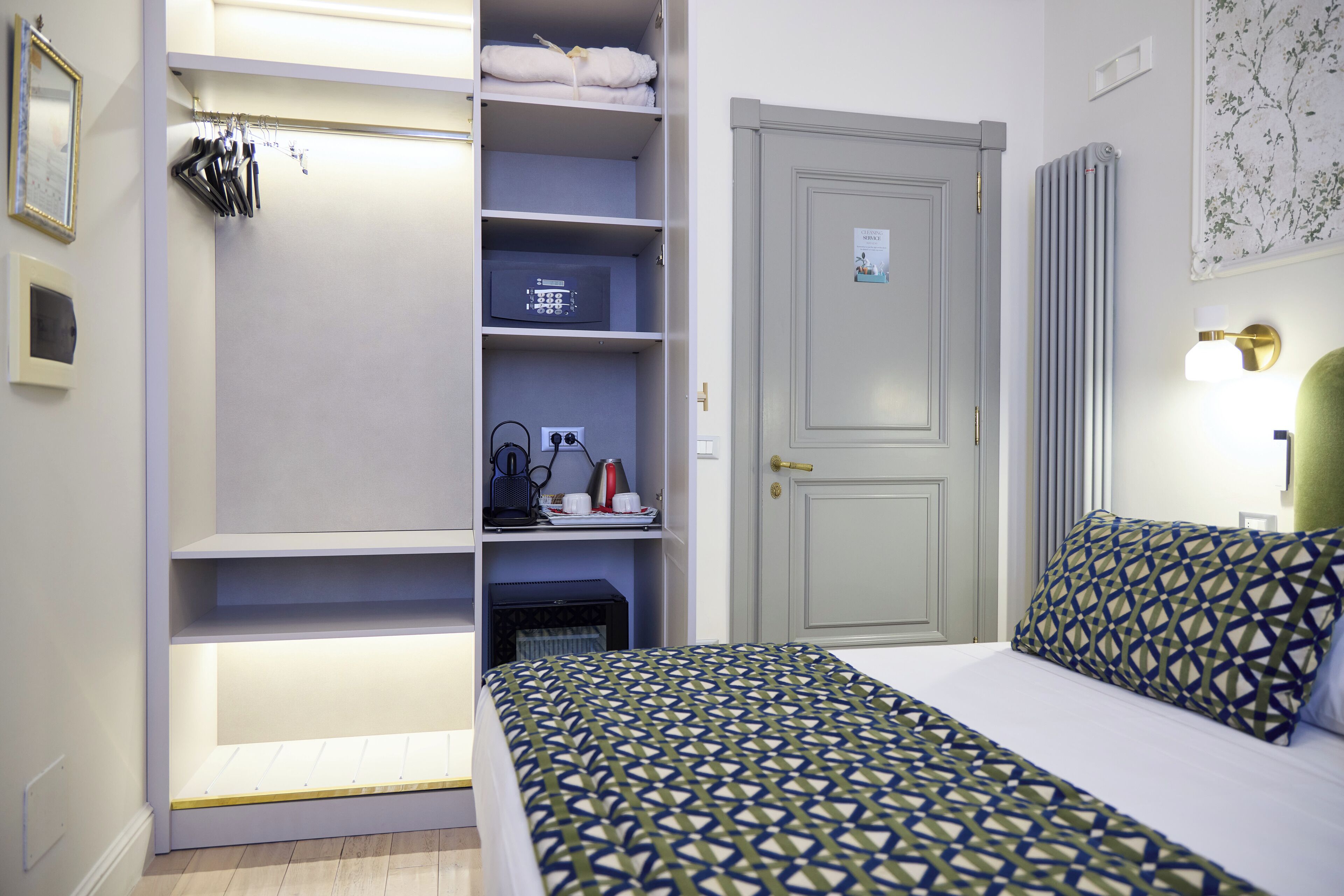 A hotel room with a bed, a wardrobe, and a door.